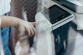 Touching the Future: Businesswoman's Hand Pressing the Copy Machine Button in a Modern Office, Reflections in the Window
