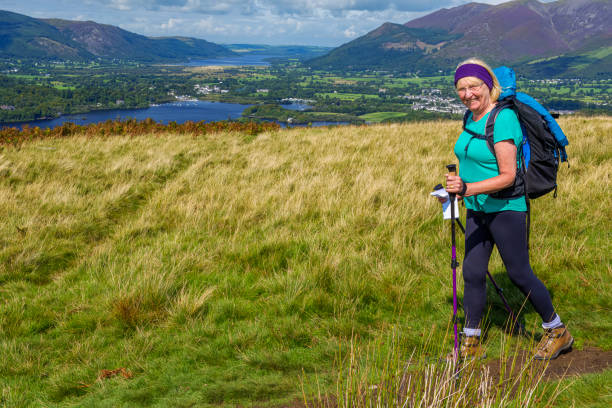 senior female hiker with walking poles and backpack hiking to walla crag in the lake district of cumbria, england. - cumbria hiking keswick english lake district imagens e fotografias de stock