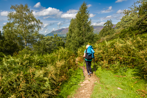Senior female hiker walking from Walla Crag, a viewpoint just south of Keswick overlooking Derwent Water in the Lake District of Cumbria, England.