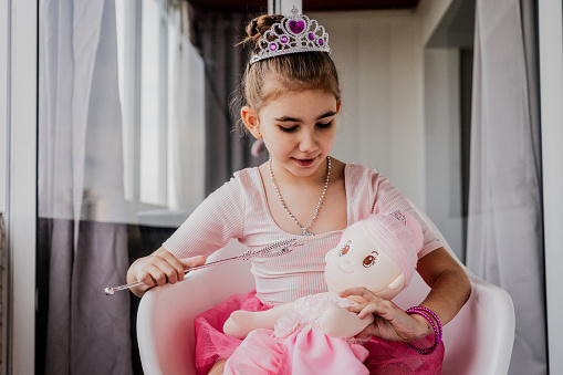 Child girl playing with her doll at home