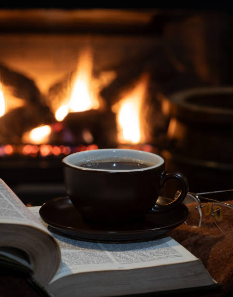istock Cup of coffee with burning fireplace in background 1897327005
