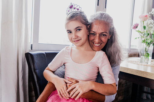 Portrait of a grandmother and granddaughter embracing at home
