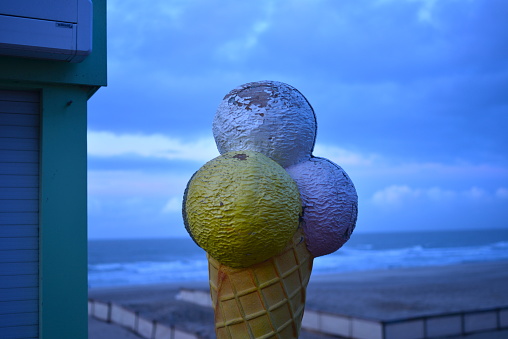 Blankenberge, West-Flanders, Belgium - December 29, 2023: close-up on giant 3D painted fiber glass model of an ice-cream on a cone displayed outdoors on the beach promenade at sunset