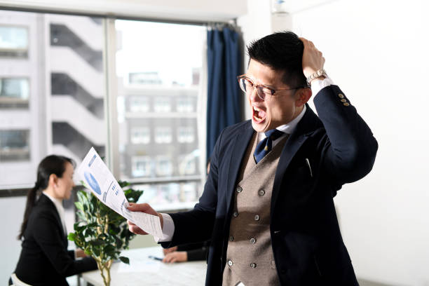 istock A young Asian man in a suit holding his head while checking documents in the office 1897452005