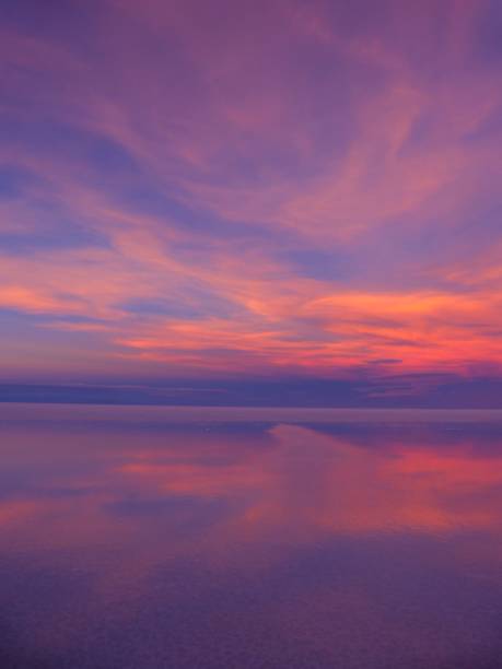 istock Bright sunset dusk pink orange blue sky clouds over lake water. 1897500217