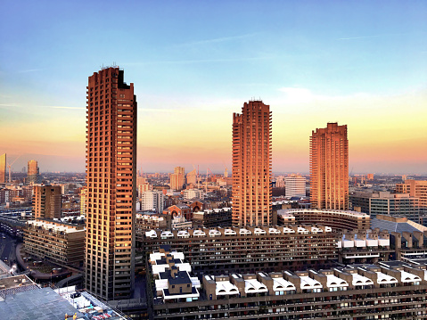 A view of high rise apartment blocks, examples of brutalist architecture, in the Barbican area of central London at sunset.