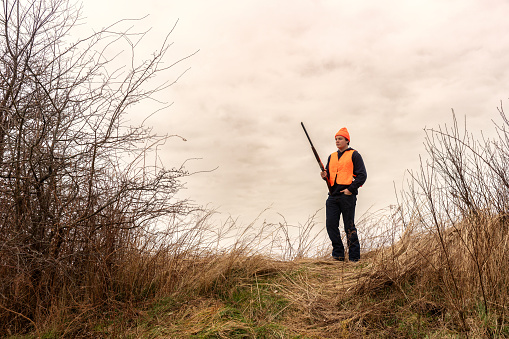 A young male hunter holding shotgun while out bird hunting in the winter
