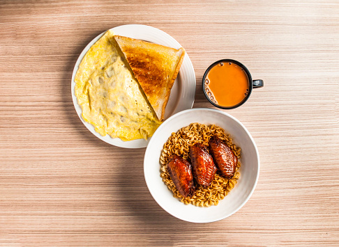 chicken wings noodles set with omelette, bread toast and coffee served in dish isolated on table top view of hong kong breakfast food