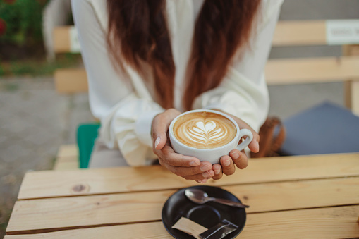 Cropped Image of Woman Hands Holding a Coffee Cup in Outdoors Cafe