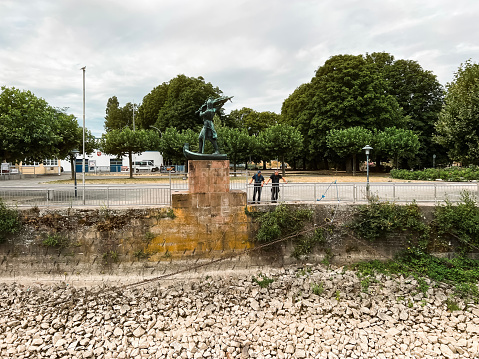 Rüdesheim am Rhein, Germany Europe, July 21, 2023, Two workers inspect their work after securing a large ship vessel to shore. Rocky riverbed shore in the forefront of view.