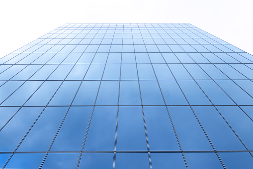 A close up photograph of the glass facade of a modern skyscraper.