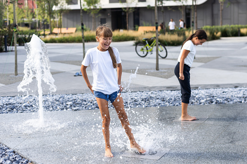 On a hot day, children run and have fun at the city fountain. Leisure time concept. summer holidays. happy childhood. High quality photo