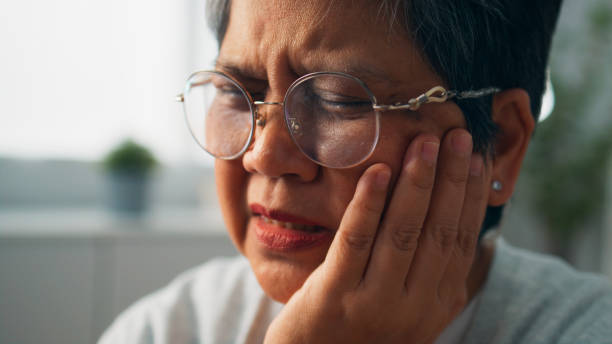 istock Senior Asian woman touching cheek with dental problem while sitting on couch at home, Unhappy grandmother suffering from sensitive teeth, Elderly woman having teeth pain 1897780448
