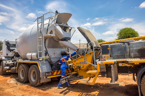 African worker on a construction site loading the boom concrete pump from the truck with the concrete mixer