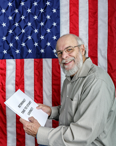 A smiling senior adult man showing a thumbs up hand gesture is reading a simulated USA Social Security and/or financial planning information document titled: \
