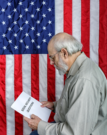A senior adult man is reading a simulated USA Social Security information document titled: \