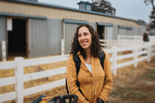 Portrait of an Eurasian woman smiling and standing outside a barn while at an Autumn fair with her family.