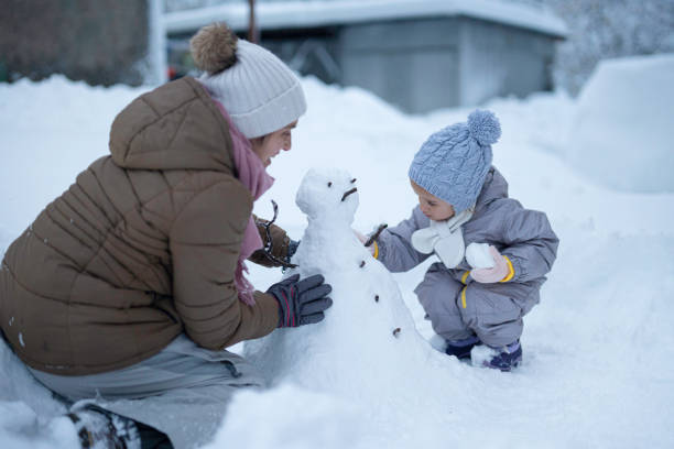 istock Making My First Snowman. Child with Mother Outdoors in Winter 1898215935