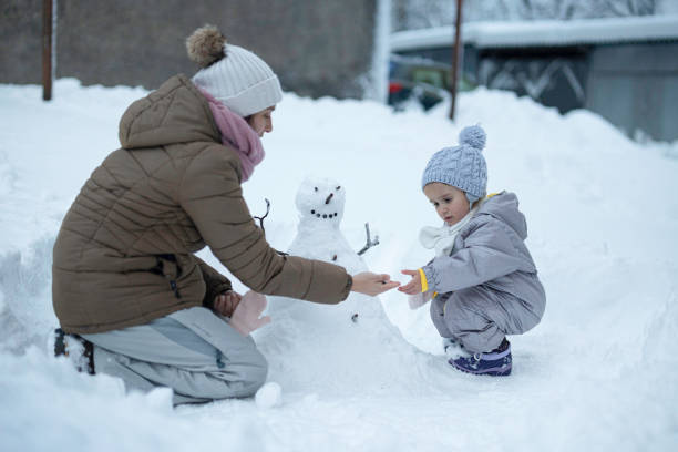 istock Family Fun in First Snow. Mom and Kid Making Snowman 1898215937