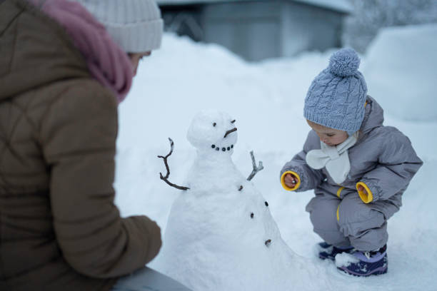 istock Making My First Snowman. Child with Mother Outdoors in Winter 1898216059