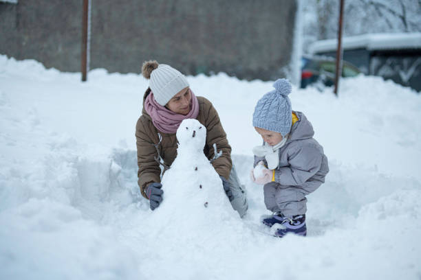 istock Family Fun in First Snow. Mom and Kid Making Snowman 1898216068