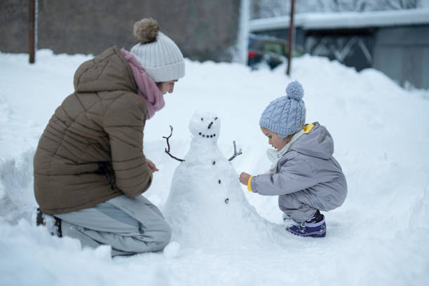 istock Making My First Snowman. Child with Mother Outdoors in Winter 1898216069