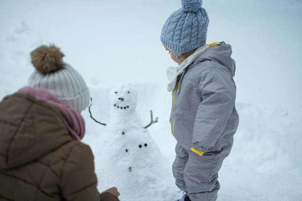 istock Family Fun in First Snow. Mom and Kid Making Snowman 1898216072