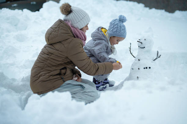 istock Family Fun in First Snow. Mom and Kid Making Snowman 1898216083