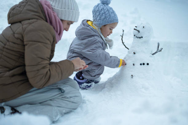 istock Making My First Snowman. Child with Mother Outdoors in Winter 1898216084