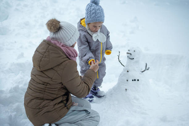 istock Family Fun in First Snow. Mom and Kid Making Snowman 1898216089