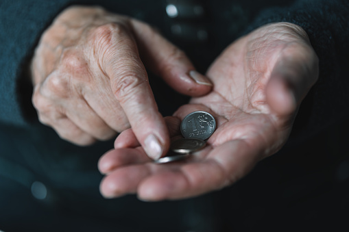 Elderly woman counts russian rubles in coins, wrinkled female hands close up. Concept of poverty in Russia, pension payments, pensioner with metal money. poverty of Russian pensioners.