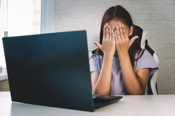 istock scared little girl closing face with hands looking at laptop screen. prohibited information on Internet for children. the concept of age censorship. 1898218239