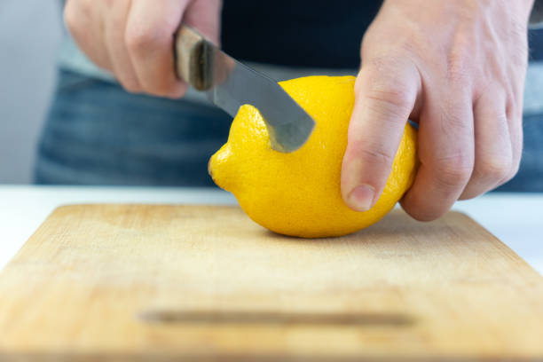 istock Cut the lemon. Men's hands slice a lemon on wooden cutting board 1898218778