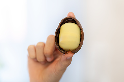 chocolate egg in the hands of a teenage girl close-up. A child opens a chocolate egg.