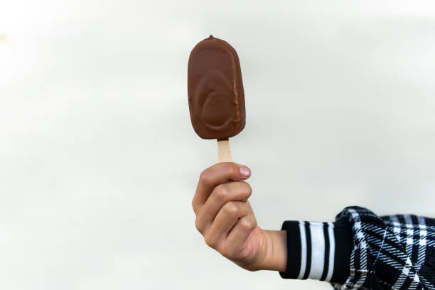 sorvete coberto com palitos de chocolate e amêndoas na mão fundo branco. - people snack almond brown - fotografias e filmes do acervo