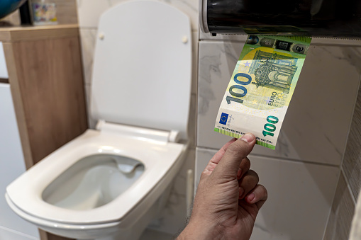 Flush money down toilet, throws euro bills in the toilet, loss concept, close up, selective focus. concept of senseless waste of money, loss, useless waste, large water costs,