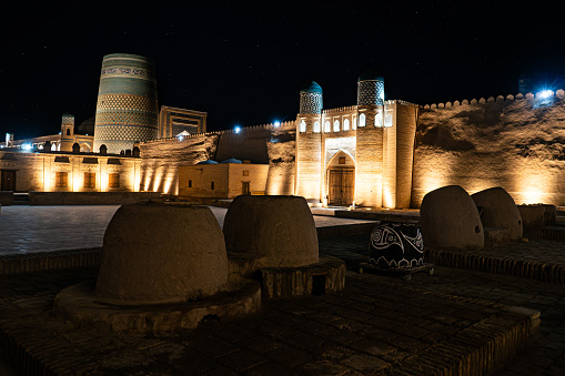 Traditional tandoor ovens for baking bread on background of Kunya Ark fortress and Kalta minor Minaret in Khiva, Uzbekistan