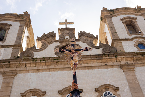 Salvador, Bahia, Brazil - August 12, 2022: Catholic is seen raising the cross of Jesus Christ in front of the Senhor do Bonfim Church in the city of Salvador, Bahia.