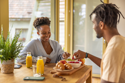 Diverse young adult couple enjoying a colorful breakfast at weekend getaway. Getting away from everything and spending some quality time together.