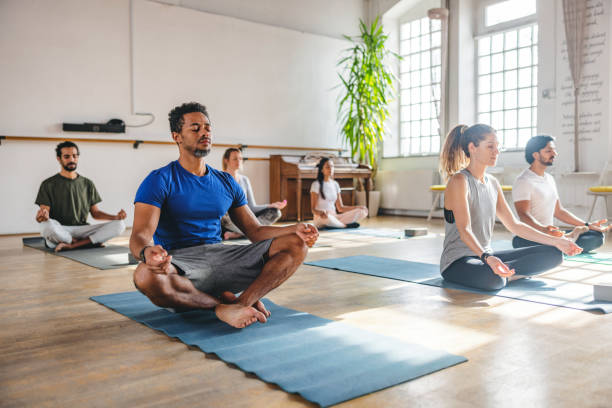 istock Multiracial Group Meditating During A Yoga Class In A Beautiful Studio With Big Windows 1898252706
