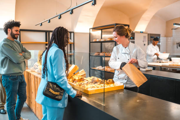 istock Lovely Caucasian Shop Assistant Serving Costumers In An Artisan Bakery 1898253247