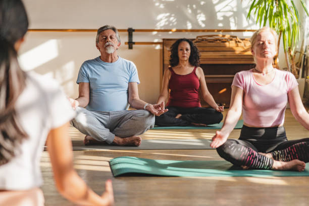 istock Mature Yoga Participants Meditating With Female Instructor 1898253791