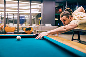 An amateur player playing pool game in a billiard hall.