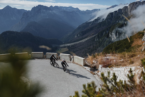 In this photo, road cyclists climb a mountain road, training hard for a triathlon. They wear their cycling gear, helmets, and gloves, showcasing their dedication to the sport.