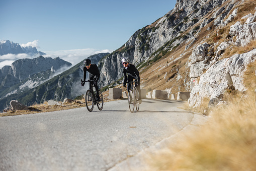 A photo showcases the power and speed of professional cyclists as they ride their road bike through hilly terrain.