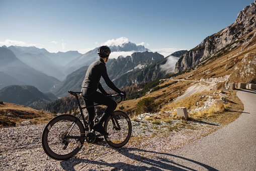 A determined cyclist riding his road bike through a stunning natural setting. With the blurred background and the cyclist in focus, the photo emphasizes the feeling of speed and the athlete's determination.