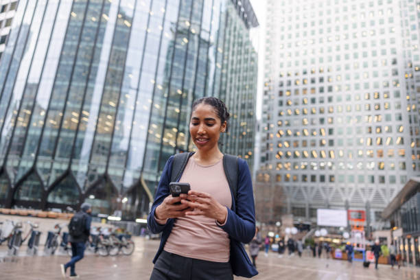 istock Dark-Skinned Business Woman Holding Her Cellphone And Reading Something On It While Walking Outside At A Business District 1898256492