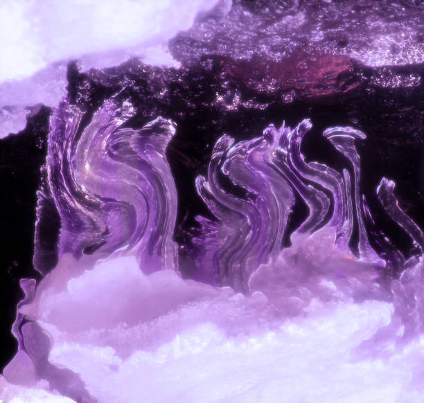 Abstract photo of curvy, transparent structures in shades of purple, reaching toward the top.  they are against a dark background, with shades of purple and white above and below. stock photo