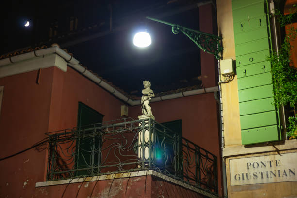 Venice Italy - May 10 2011; Statue on balcony illuminated by street light  over canal bridge