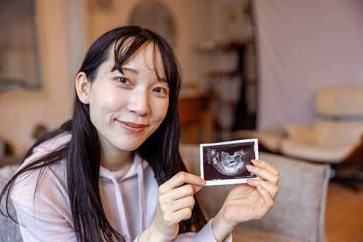 Happy pregnant woman showing ultrasound photo of an unborn baby